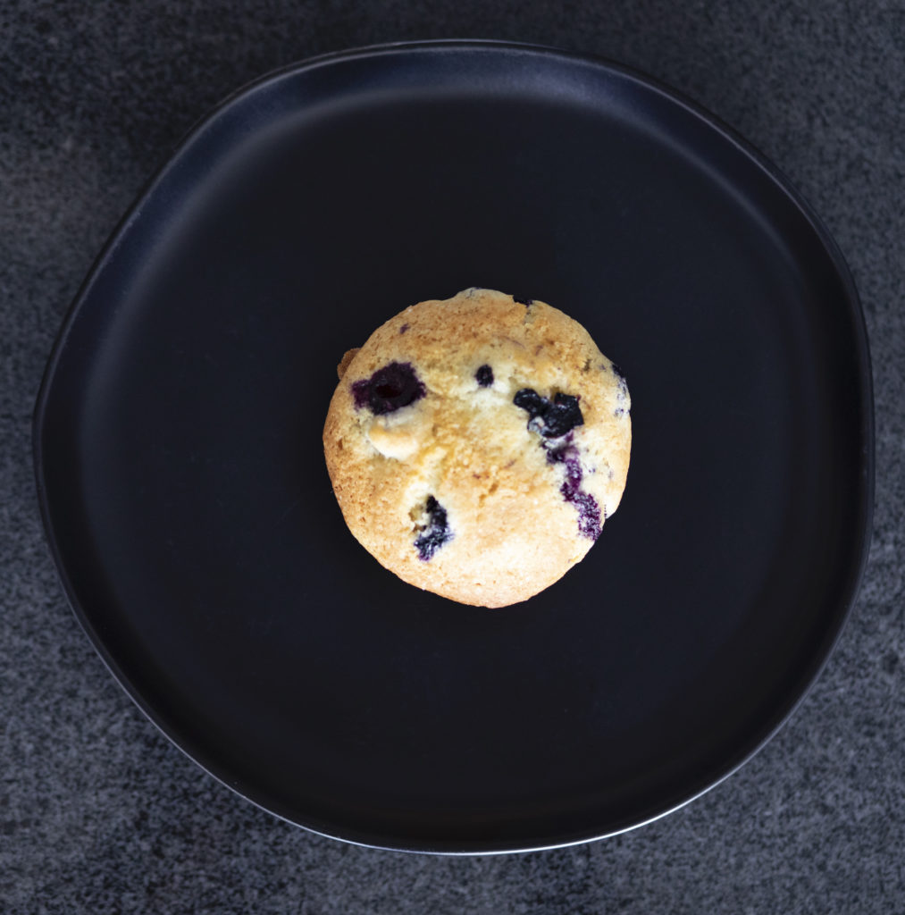 Top Down View of Blueberry Muffin on Black Plate